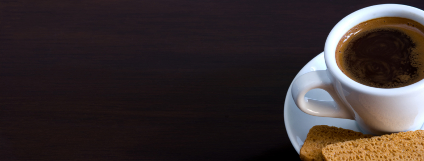A cup of coffee with biscuits on a table.