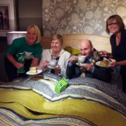 A group of people standing on a bed with a cup of tea.
