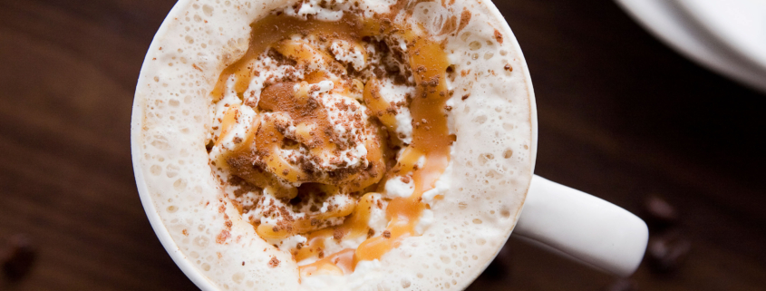 A cup of coffee with whipped cream and chocolate chips.