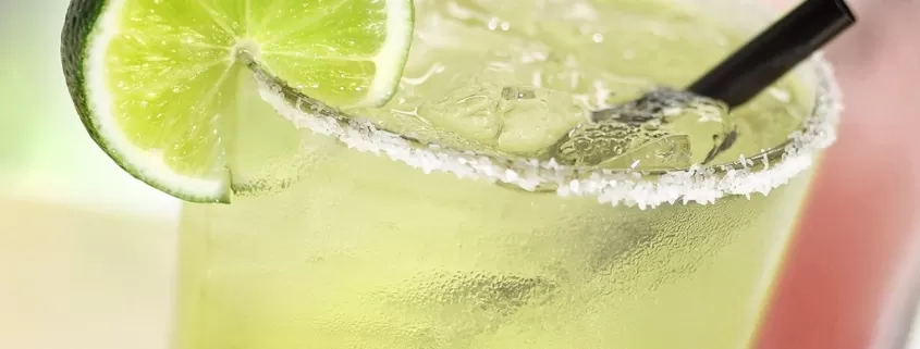 Two lime margaritas on a table.