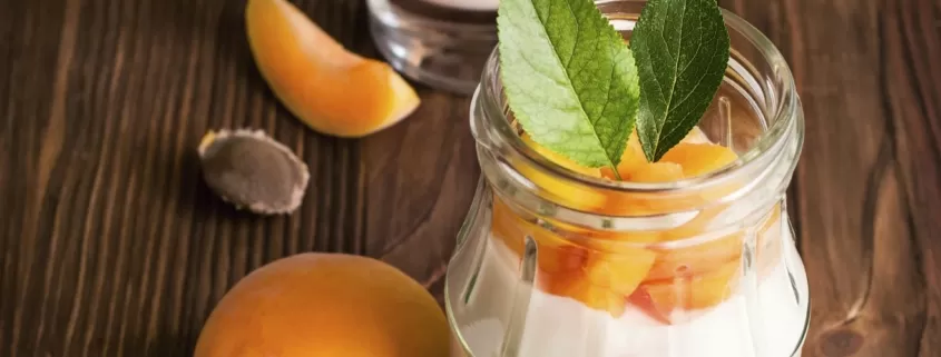 Two jars of yogurt with apricots in them.