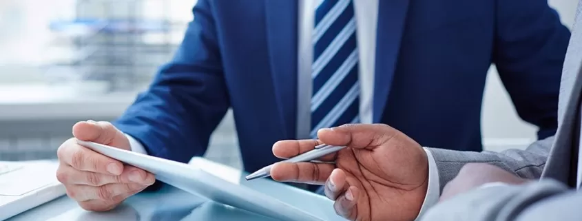 Two businessmen in suits sitting at a desk.
