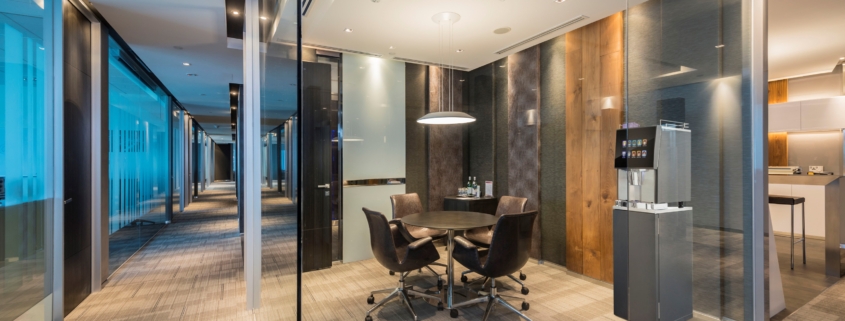 A glass walled office with a table and chairs.