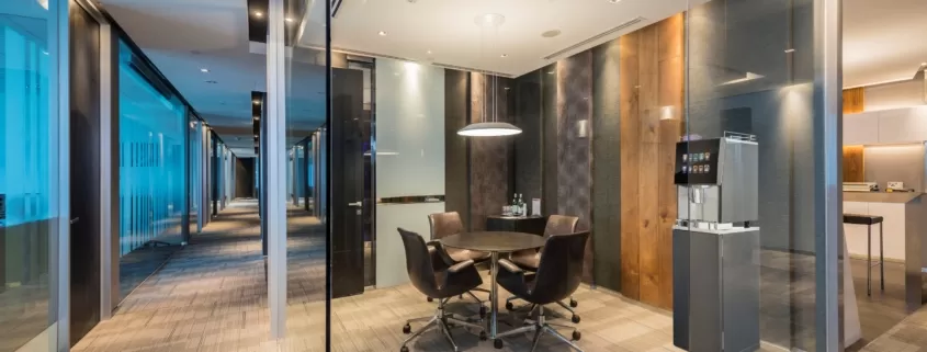 A glass walled office with a table and chairs.