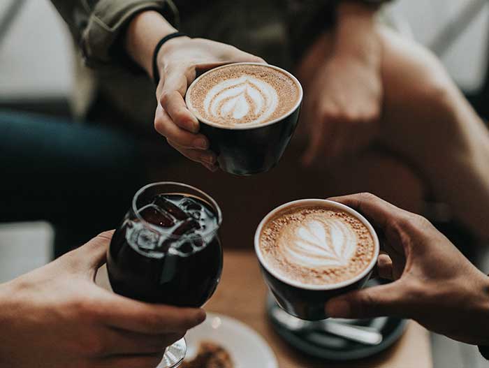 drinks-group-01 A group of people toasting a cup of coffee at a vending machine.