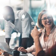 How to achieve a happy and healthy workforce. A group of people sitting around a table with pizza, fostering a happy.