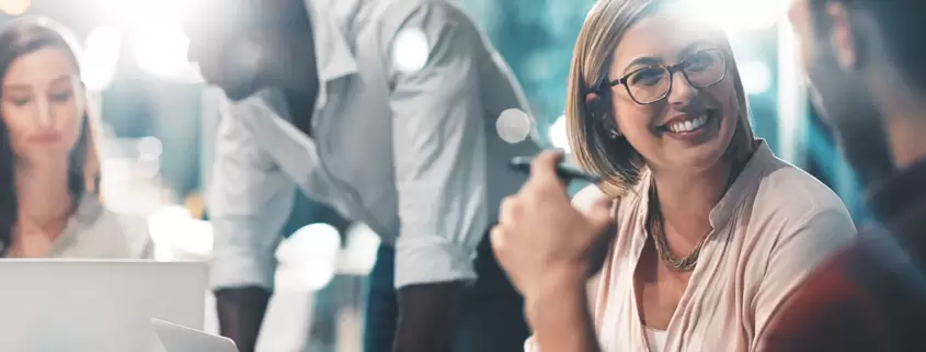 A group of people sitting around a table with pizza, fostering a happy.