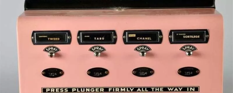 A pink machine with four buttons on it that dispenses perfume.