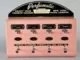 A pink machine with four buttons on it that dispenses perfume.