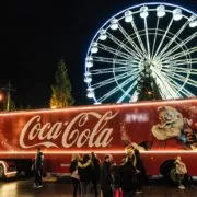 Coca-Cola Christmas Truck in Manchester, England A Coca-Cola truck in front of a ferris wheel at Christmas.