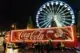 A Coca-Cola truck in front of a ferris wheel at Christmas.