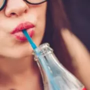 A woman is drinking a popular soft drink from all around the world.