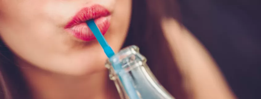 A woman is drinking a popular soft drink from all around the world.