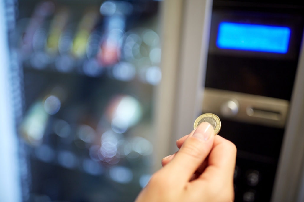 hand inserting euro coin to vending machine slot