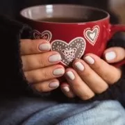 Woman with beautiful manicure holding a red cup of tea We all love a cup of tea, but what country consumes the most?