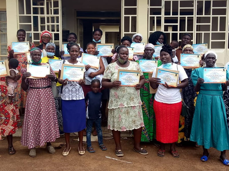 covid_jsc A group of women holding certificates in front of a building after a just small change.