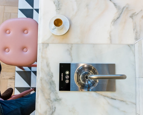Gallery-2 A man sitting on a marble counter with a cup of coffee.