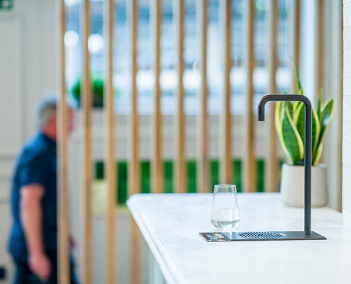 Gallery-3 A man is standing in front of a counter with a bottle of water on it.