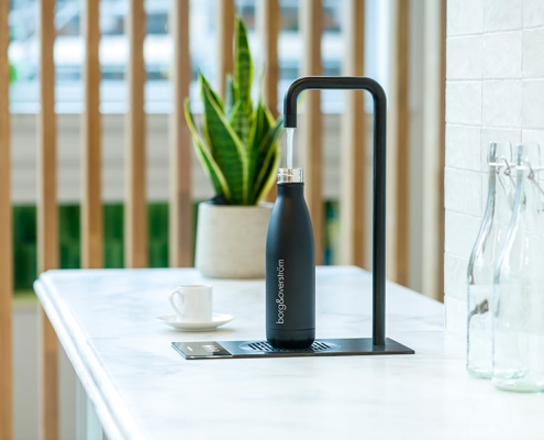 Gallery-4 A black bottle is sitting on a counter in a kitchen.