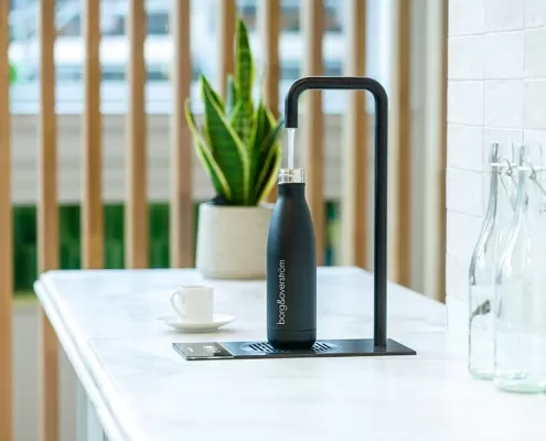 Gallery-4 A black bottle is sitting on a counter in a kitchen.