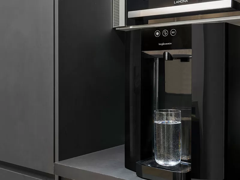 A water dispenser with a glass of water on it, featuring the Borg E4.