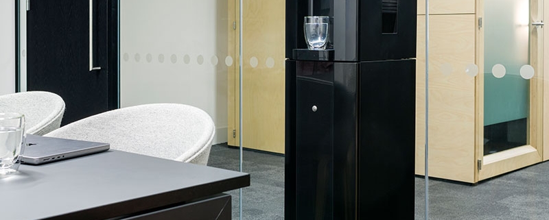 A black water dispenser in a conference room.