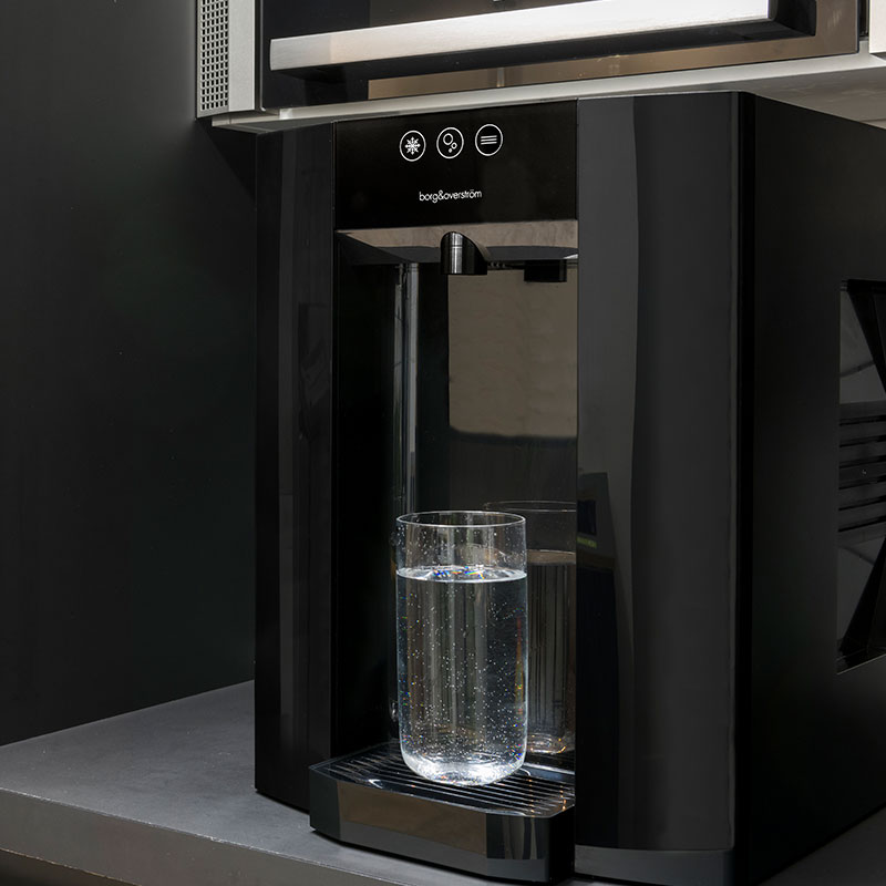 Borg-Story-1 A black water dispenser with a glass of water.