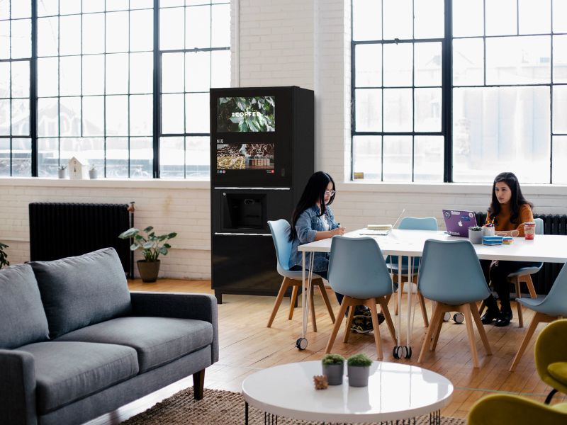 Hot Drinks Vending Machine A group of people sitting around a table in an office.