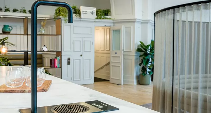 A water dispenser tap in a smart, modern office environment.